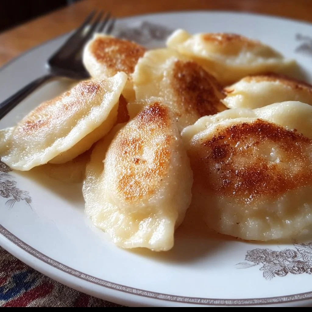 Plate of gluten free perogies with a side of sour cream and herbs.