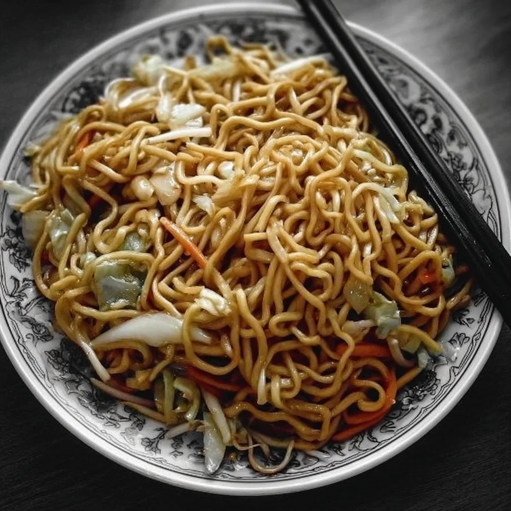 A plate of flavorful fried noodles garnished with vegetables and herbs