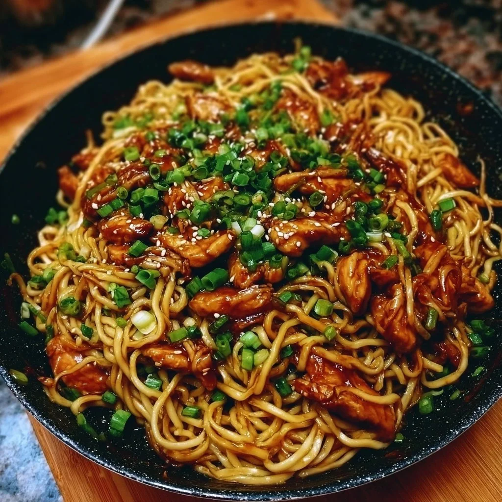 Delicious sticky garlic chicken noodles served in a bowl with fresh herbs